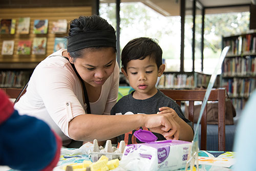 A mother helps her son with an arts and crafts project.