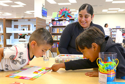 Photo of adult with two children reading alphabet tiles.