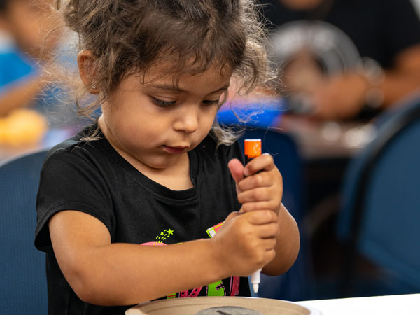 A child creates a craft involving markers and rocks.