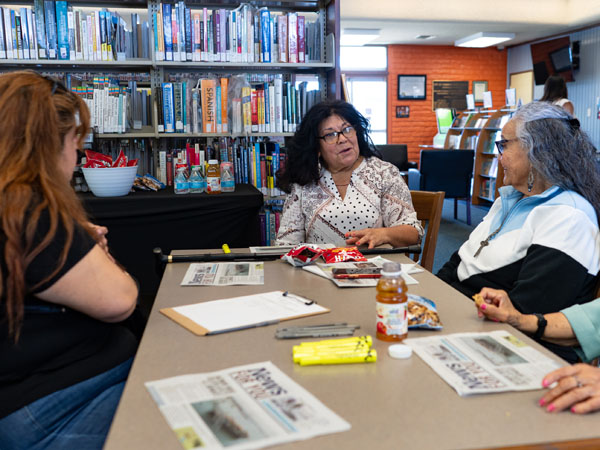 Adults gathered at a table to discuss a newspaper story.