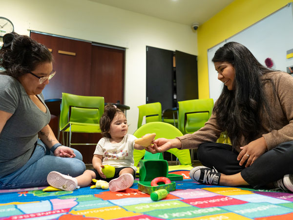 A library staff member interacts with parent and child at play time.