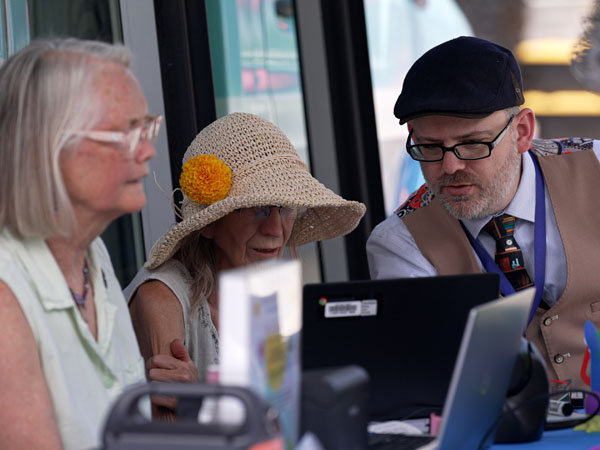 A library staff member helps two women use a computer at a bookmobile stop.