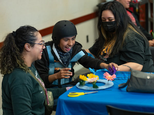 Three people at a table making a craft and smiling