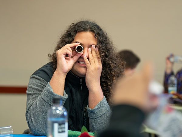 Person covering one eye, and holding a small tube up to the other eye 