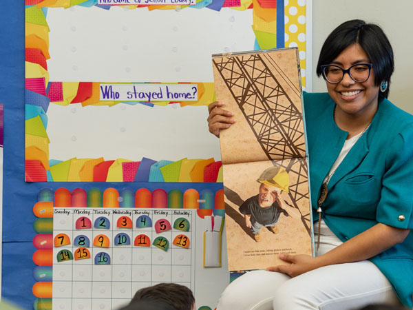 A library worker displays a book to young children in a classroom storytime environment.