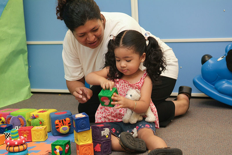 A mother and daughter play with blocks.