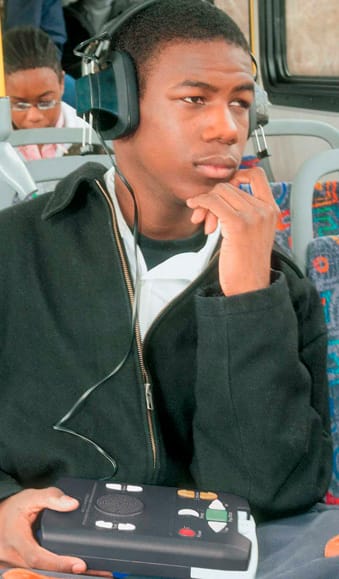 A young African-American man listening to an audio book.