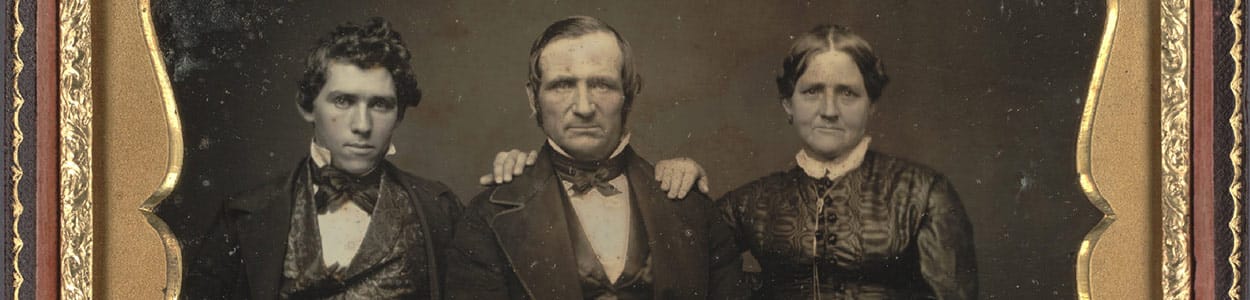 Black and white photo portrait of two men and a woman in Gold Rush era clothing.