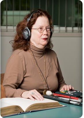 Woman wearing glasses and using braille and talking books.