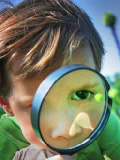 A kid looking through the magnifying lens