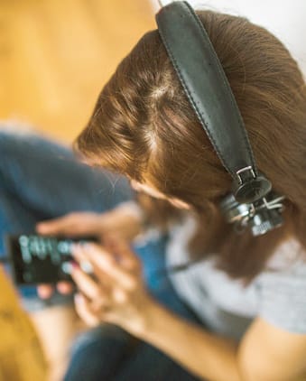 Photo of a girl with a smart phone and a headset.