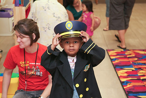 A young child dresses up in an airplane captain uniform, complete with hat.