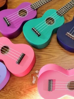 Several colorful ukuleles on a wooden table