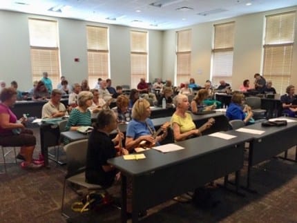 Adults learning ukulele in an ukulele program in a library.