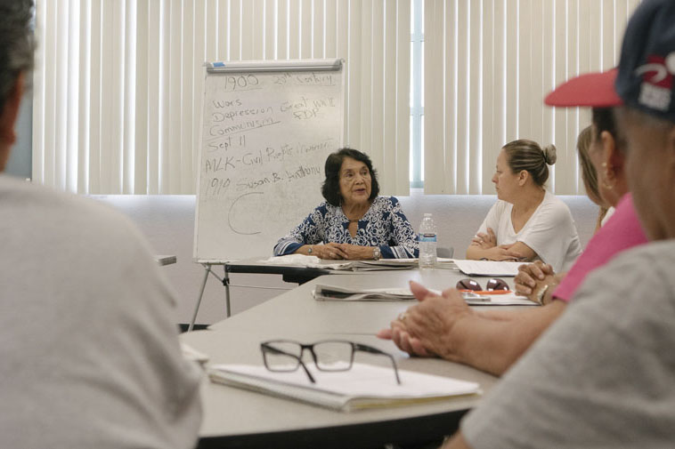 Woman talking to a group of adults in a round-table history discussion. Photo courtesy of the Los Angeles Public Library