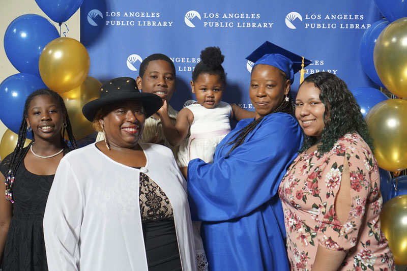 Family group celebrating a female in a cap and gown at her Career Online High School Graduation. Photo courtesy Los Angeles Public Library.