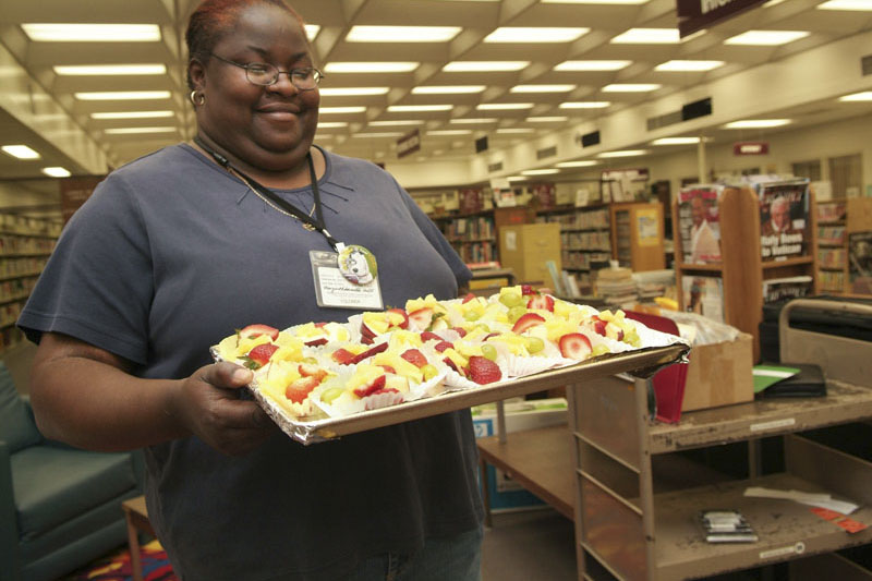 Female library staff member or volunteer holds a tray of healthy snacks make up of fruit for an event. Photo copyright Terry Lorant.