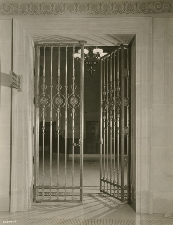 Black and white photo of an ornate metal gate inside a building.