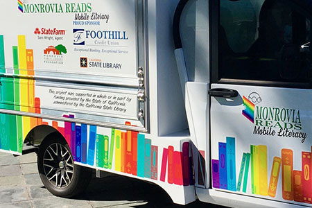  Photo of the side of a bookmobile that has pictures of books and says “Monrovia Reads Mobile Literacy”.